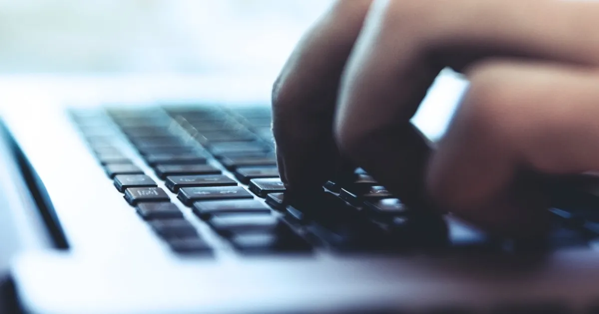 Hands typing on a laptop keyboard