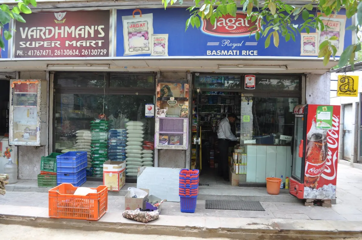 Front of a small supermarket in India with crates and a cold-drink fridge outside